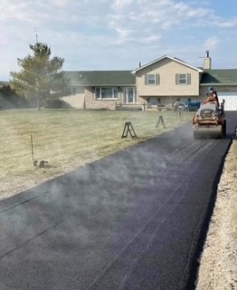 Freshly paved asphalt driveway through a yard
